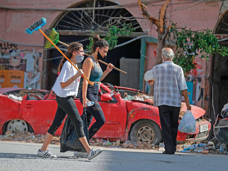 لبنانيتان تتطوعان لتنظيف شوارع بيروت المتضررة في الجميزة أمس (أ ف ب)n