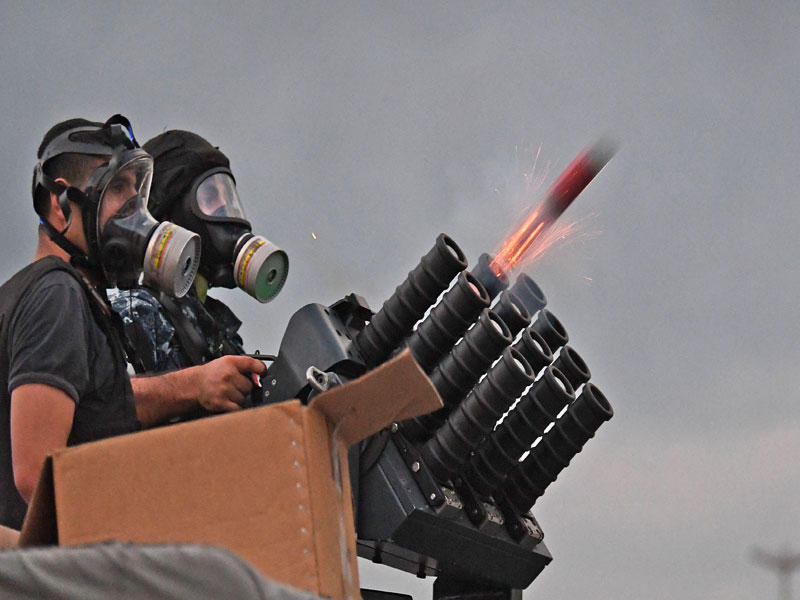 رجلا أمن يطلقان قنبلة غاز مسيل للدموع خلال مواجهات بيروت أمس الأول (ا ف ب)