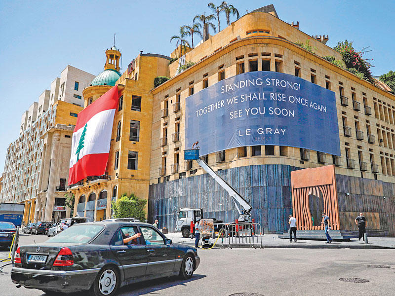 علم لبناني مرفوع على فندق «لو غراي» الذي يتم ترميمه في بيروت أمس (ا ف ب) 