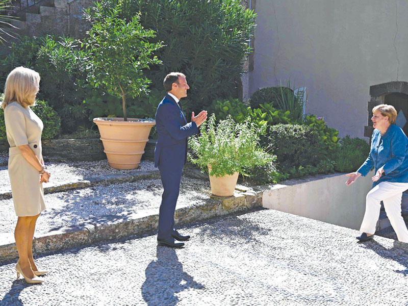 ماكرون وزوجته بريجيت يرحبان بميركل في بريغانسون أمس (أ ف ب) 