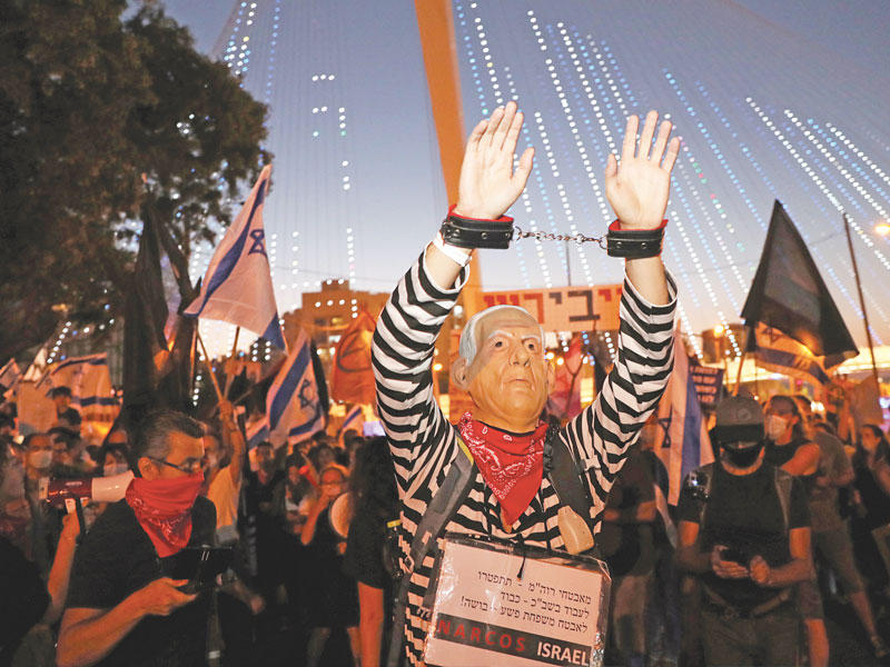 متظاهر مقيد اليدين يرتدي قناعاً يمثل وجه نتنياهو خلال تظاهرة معارضة في القدس أمس الأولt (رويترز)