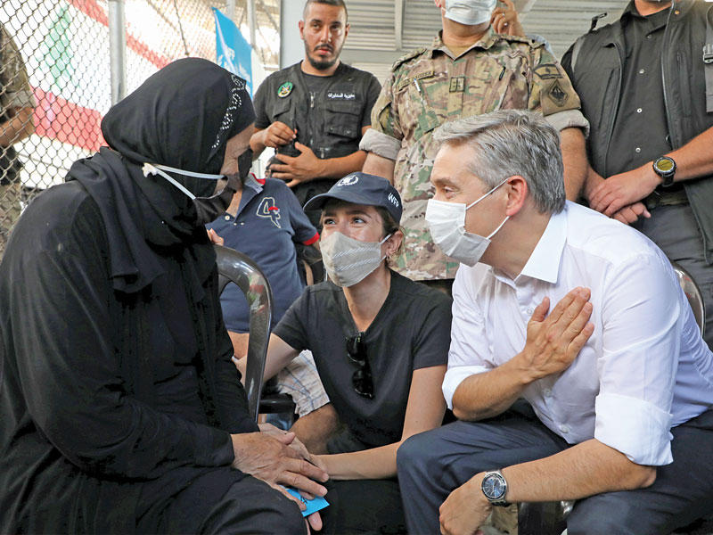 وزير الخارجية الكندي مستمعاً إلى سيدة خلال جولته في مرفأ بيروت أمس   (رويترز)
