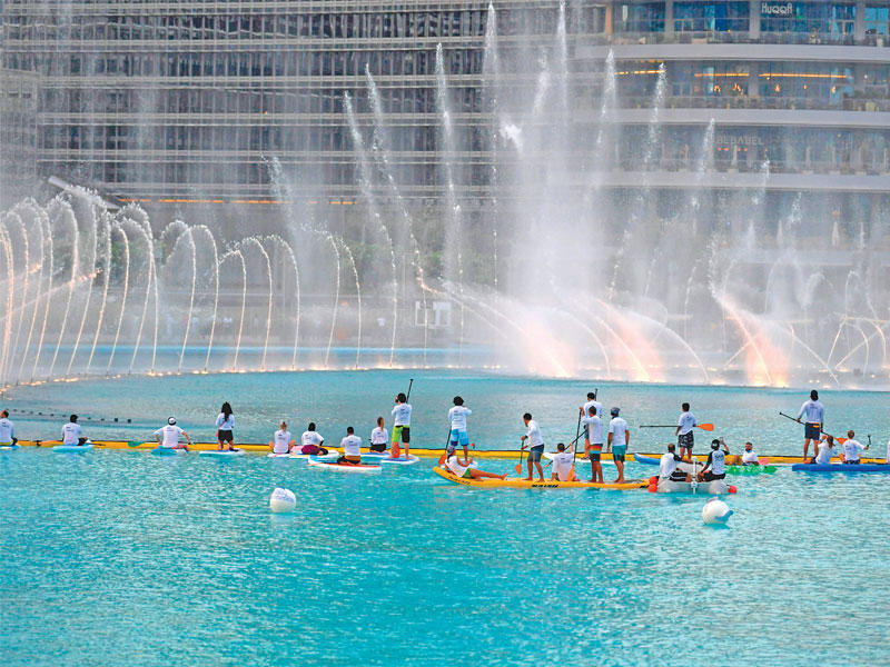 مجموعة أشخاص يمارسون هواية التجديف في مياه البحيرة المحيطة ببرج خليفة في دبي أمس الأول (ا ف ب)