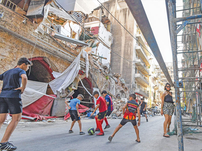 أطفال يلعبون كرة القدم في منطقة الجميزة بالأشرفية التي تضرّرت بانفجار مرفأ بيروت (ا ف ب)