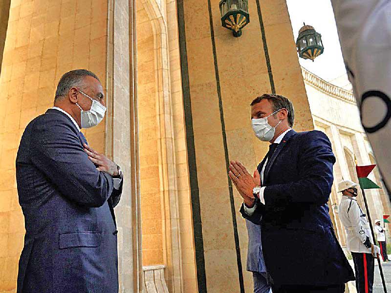 مصطفى الكاظمي وماكرون وتحية «كورونا» في بغداد أمس (أ ف ب)