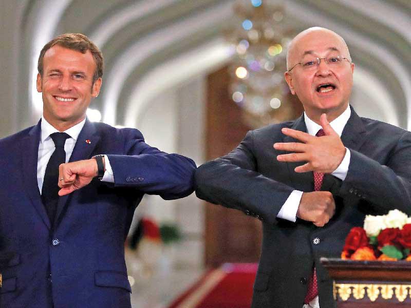 الرئيس الفرنسي إيمانويل ماكرون ونظيره العراقي برهم صالح في «تحية كورونية» ببغداد أمس t(أ ف ب)