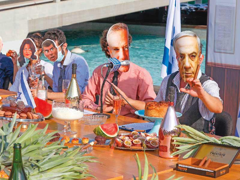 كوميديون اسرائيليون يضعون أقنعة لنتنياهو ونائبه بيني غانتس خلال تمثيلهما اجتماعاً حكومياً في تل أبيب أمس (ا ف ب)