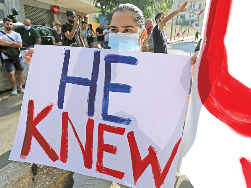 لبنانية تحمل لافتة كتب عليها «كان يعلم» خلال تظاهرة مناهضة لعون أمس (رويترز)