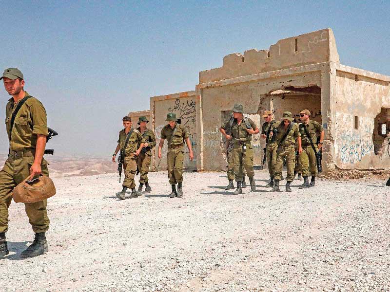 جنود إسرائيليون يخرجون من مبنى قديم شيده أردنيون خلال تدريب قرب قرية يطا جنوب الضفة الغربية المحتلة أمس (أ ف ب)