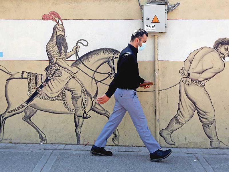 إيراني يمر أمام جدارية في طهران أمس تمثل البطل الفارسي الأسطوري روستم وهو يجر أسيراً (أ ف ب)