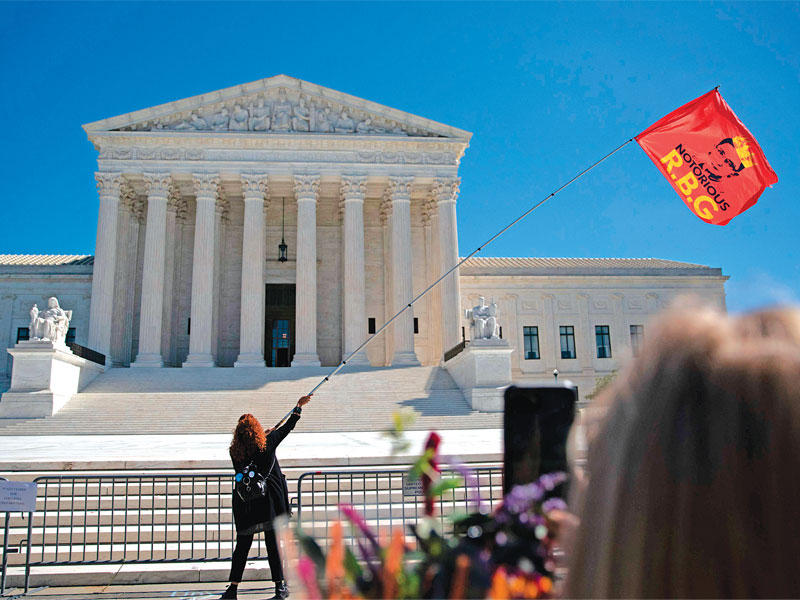 أميركية تلوح بعلم أحمر عليه صورة غينسبورغ أمام المحكمة العليا في واشنطن (أ ف ب) 