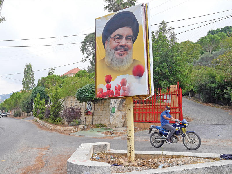 لبناني يمرّ على درّاجته النارية أمام صورة لحسن نصرالله في قرية عين قانا الجنوبية أمس t(اي بي ايه)