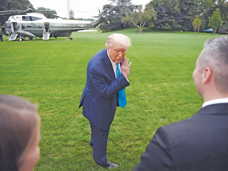 الرئيس الجمهوري دونالد ترامب يهمس لموظفي البيت الأبيض قبل استقلاله المروحية الرئاسية أمس الأول (أ ف ب) 