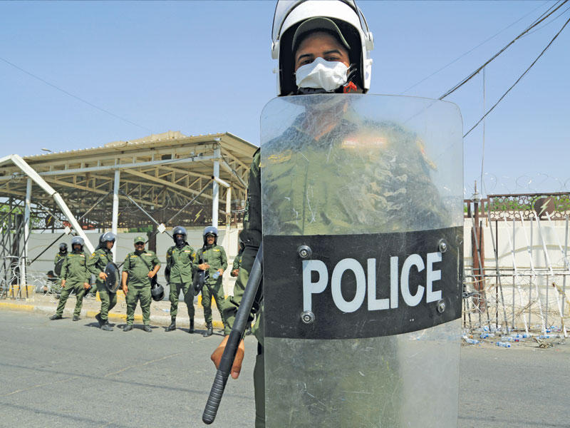 شرطي عراقي خلال تظاهرة في بغداد (رويترز)