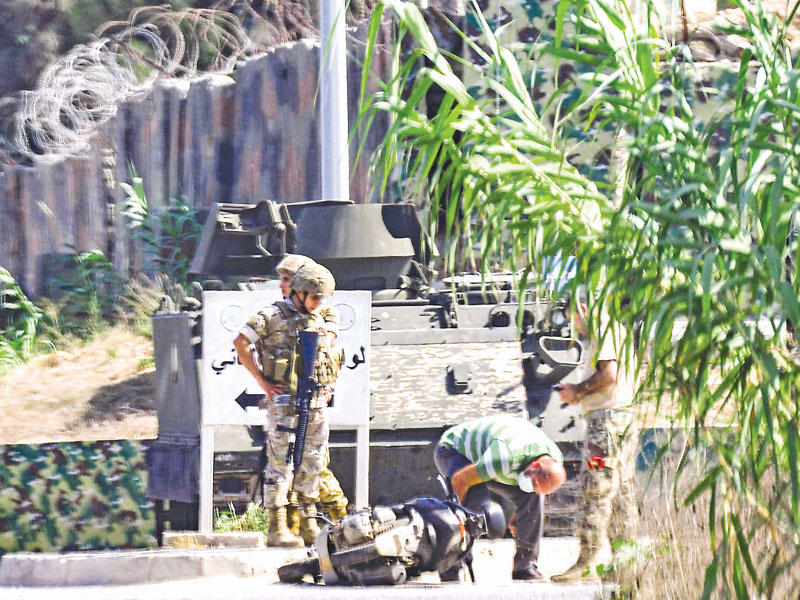 جندي وعنصر أمني يعاينان دراجة نارية استخدمها الإرهابيون في هجماتهم أمس (ا ف ب)