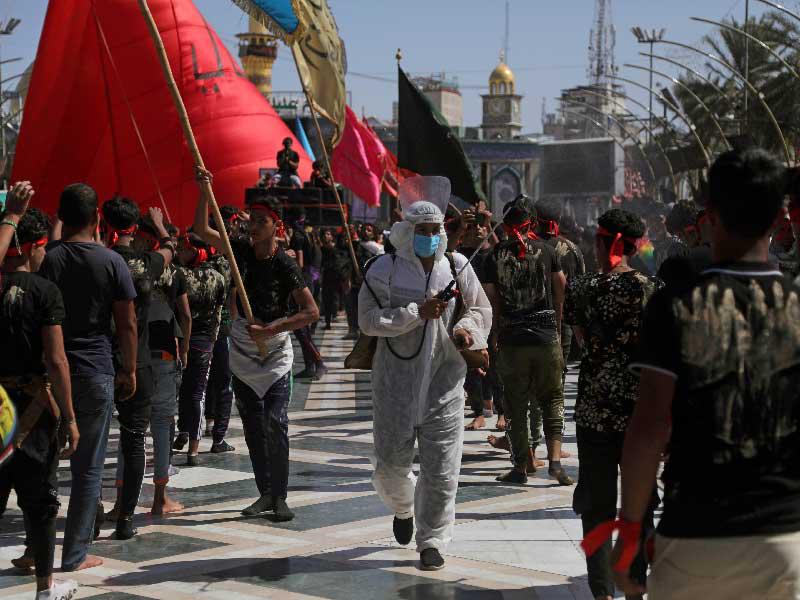 متطوع يرش مواد تعقيم أمس لحماية زوار كربلاء من فيروس «كورونا»  (رويترز)