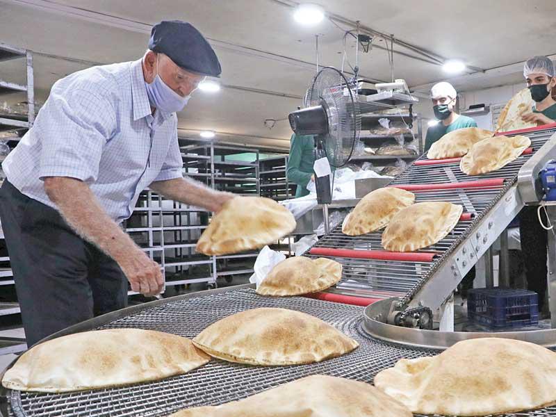 عامل لبناني مرتدياً قناعاً في أحد أفران الخبز في بيروت (رويترز)