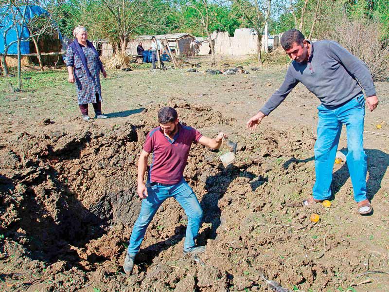 مدنيون قرب حفرة أحدثتها قذيفة سقطت في قرية قاراباغ في اقليم كاراباخ أمس (ا ف ب)