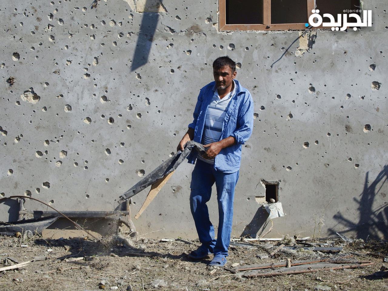 أحد سكان كاراباخ يجمع الحطام من موقع شهد قتال دام