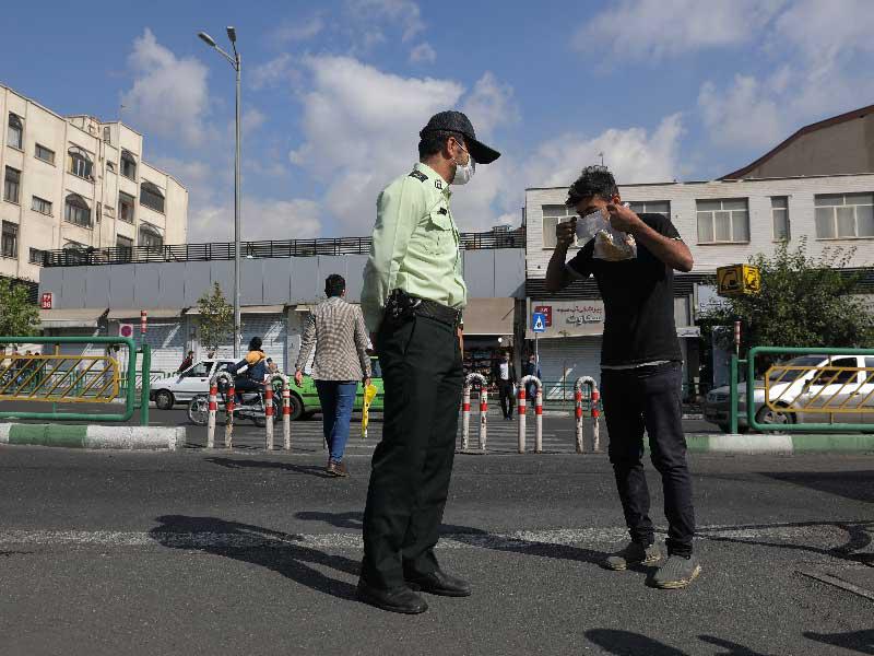 رجل أمن يلزم إيرانياً بارتداء الكمامة في طهران أمسt (رويترز)