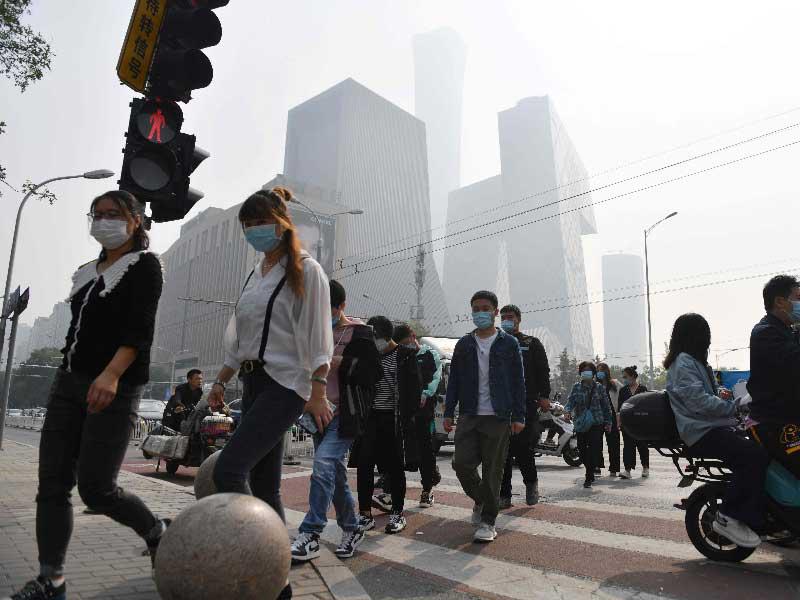 صينيون يرتدون الكمامات في أحد شوارع بكين أمس الأولt (أ ف ب)