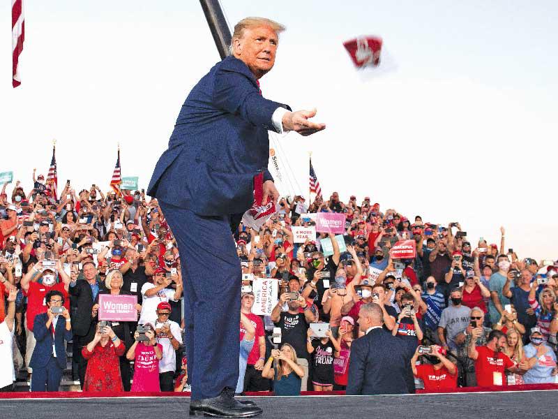 ترامب يلقي الأقنعة لأنصاره في مطار أورلاندو سانفورد الدولي بفلوريدا أمس الأول (أ ف ب)