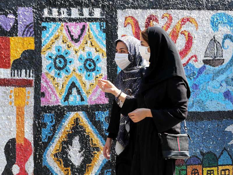 إيرانيتان تمران أمام جدارية في أحد شوارع طهران              (أ ف ب)