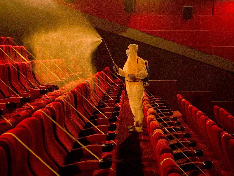 عامل يعقِّم قاعة سينما في البصرة قبل إعادة فتحها للعامةt( أ ف ب)