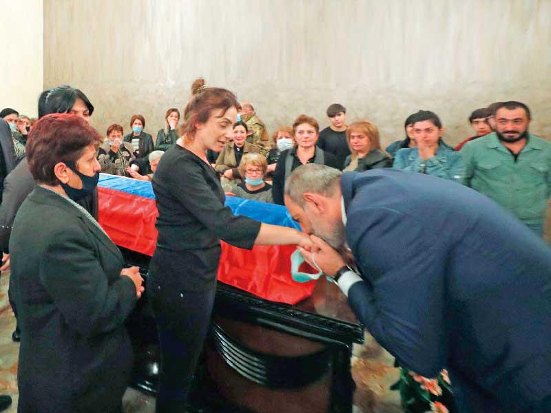 رئيس الوزراء الأرمني مقبلاً يد زوجة جندي قتل في المعارك خلال جنازته في يريفان  (ا ف ب)