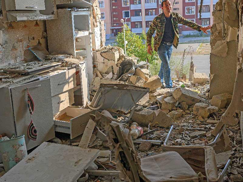 أذربيجاني يعاين شقة جيرانه في ترتار التي تضررت بالقصف الأرمني أمس الأول (ا ف ب)