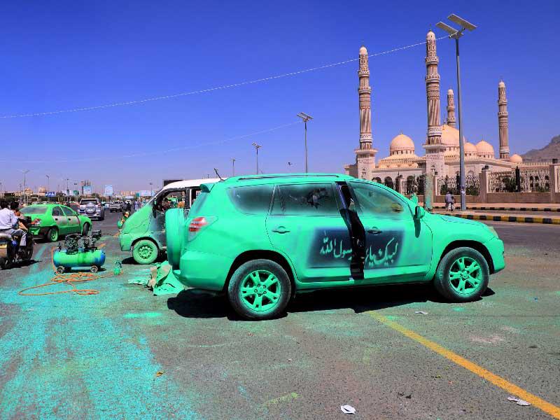 يمنيون يطلون سياراتهم باللون الأخضر خلال فعاليات احتجاجية ضد فرنسا في صنعاء (أ ف ب)