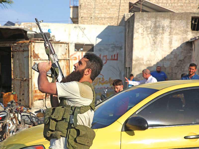 مسلح موال لتركيا يطلق النار في الهواء خلال تشييع زملائه الذين قضوا في الغارة في إدلب أمس (أ ف ب)