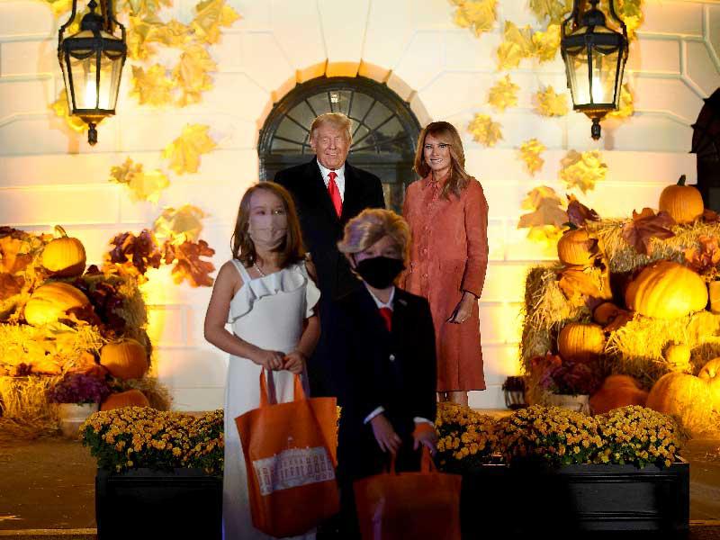 فتى وفتاة متنكران في زي ترامب وميلانيا وخلفهما الرئيس والسيدة الأولى خلال حفل هالوين في البيت الأبيض مساء أمس الأول (أ ف ب)