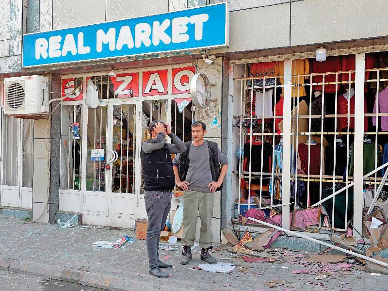 شابان أمام محلات متضرّرة بفعل القصف الأرمني في بلدة باردا أمس (ا ف ب)