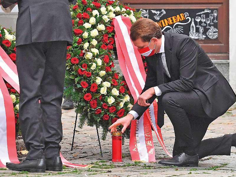 كورتس يضيء شمعة بعد وضعه إكليلاً من الزهور بأحد مواقع الهجمات في فيينا أمس (ا ف ب)