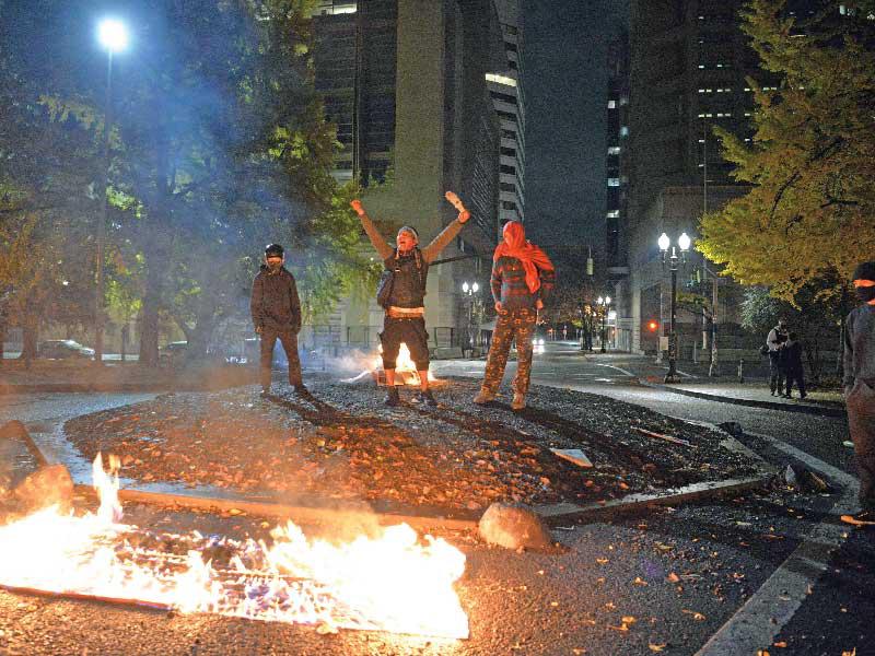 ناشطون يحرقون علماً أميركياً في أوريغون أمس     (أ ف ب)