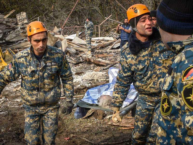 عمال الإنقاذ يحملون جثة امرأة قُتلت جراء قصف خلال الصراع العسكري المستمر بين أرمينيا وأذربيجان