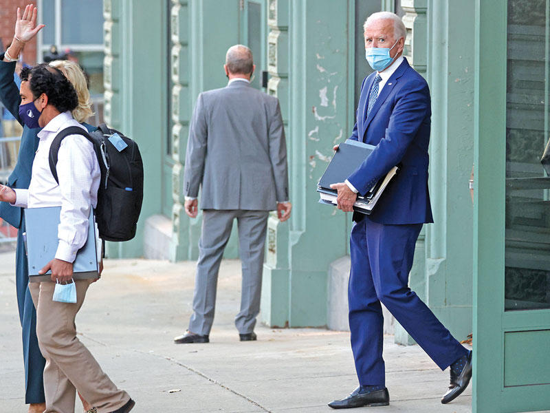 بايدن يحمل ملفاته أثناء مغادرته أول اجتماع مع فريقه الانتقالي في ويلمنغتون أمس الأول (رويترز)