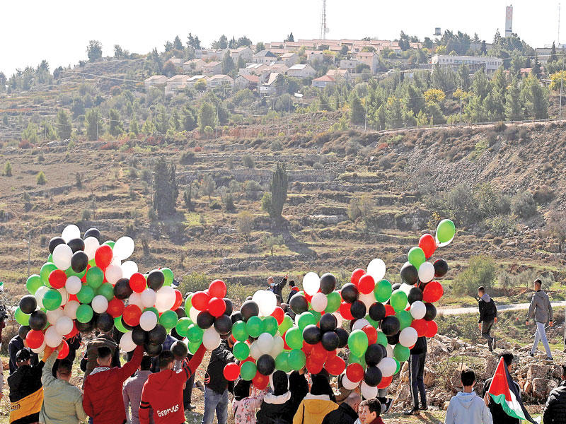 فلسطينيون يستعدون لإطلاق عشرات البالونات خلال زيارة بومبيو لمستوطنة بساغوت أمس (رويترز)