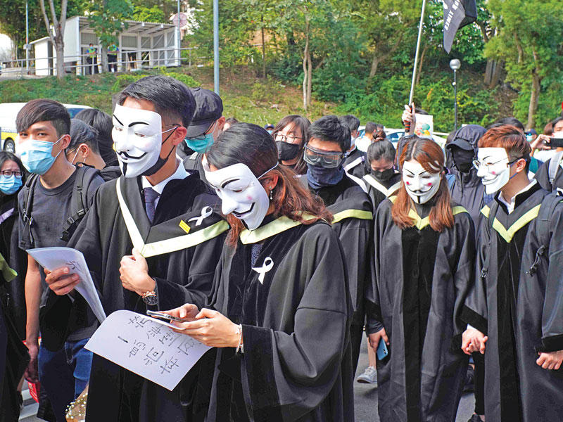 طلاب جامعة هونغ كونغ يرتدون أقنعة خلال احتجاجات مؤيدة للديمقراطية امس (أ  ف ب )