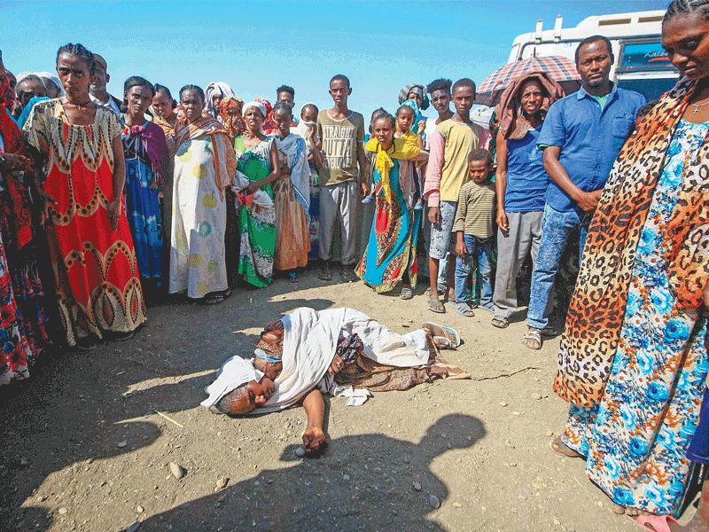 إثيوبيون يحيطون بسيدة فقدت الوعي داخل معسكر لاستقبال اللاجئين في السودان أمس الأول (أ ف ب)