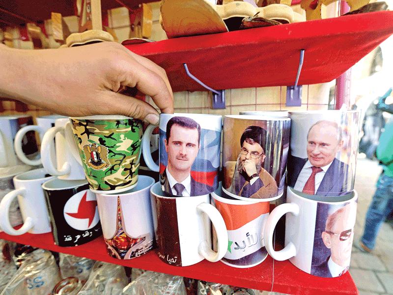 أكواب تحمل صوراً للأسد وبوتين ونصرالله معروضة للبيع في أحد أسواق دمشق (ا ف ب)