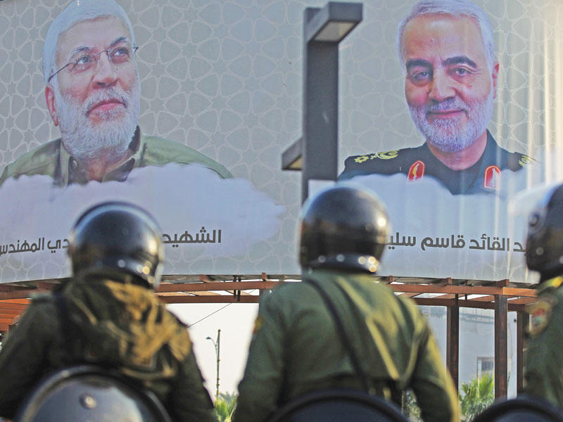 عناصر أمنية بمحيط لوحة عملاقة تحمل صورة لسليماني والمهندس بأحد ميادين بغداد الخميس الماضي (أ ف ب)