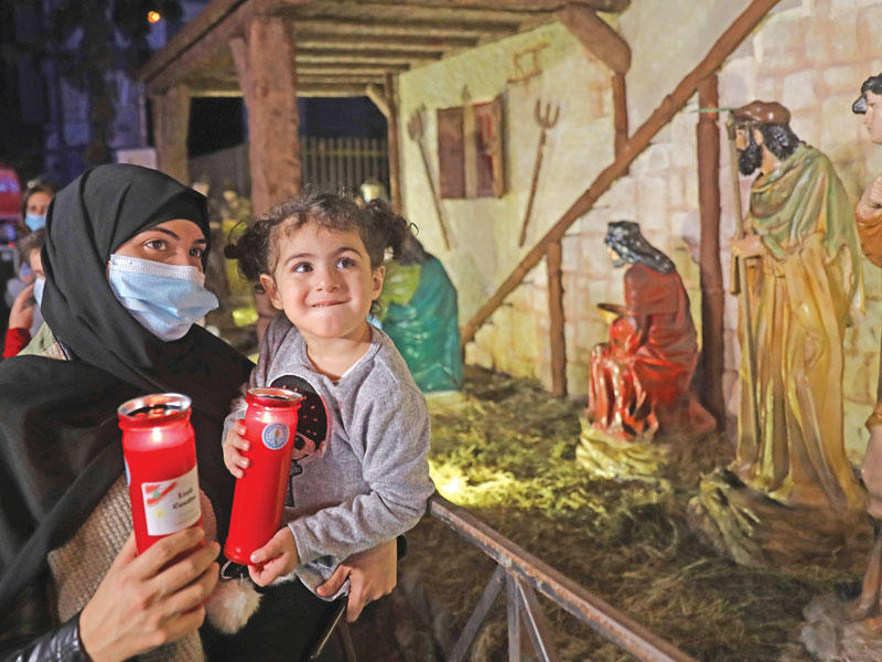 لبنانية مسلمة مع طفلتها أمام مغارة عيد الميلاد في منطقة الجميزة بالأشرفية مساء أمس الأول     (أ ف ب)