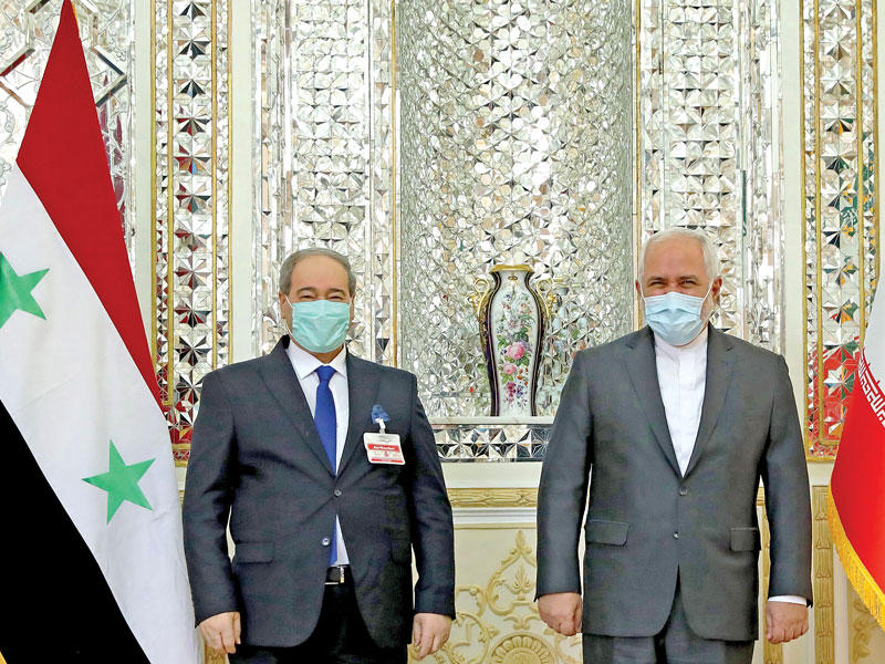 وزير الخارجية الإيراني محمد جواد ظريف مستقبلاً  نظيره السوري فيصل المقداد في طهران أمس            (أ ف ب)