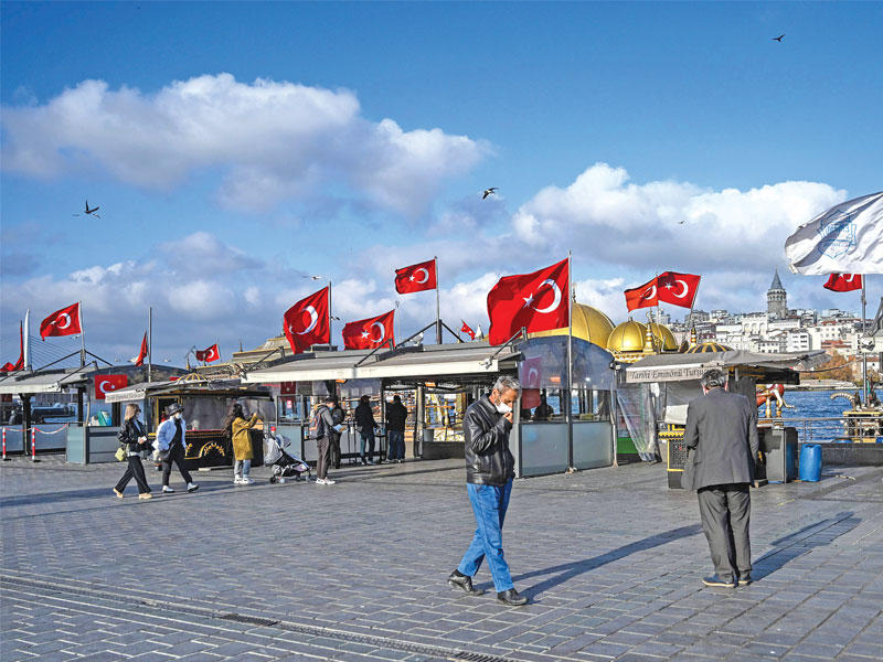 أتراك يمرّون قرب محلات مقفلة في ساحة «امينونو» بإسطنبول أمس الأول (أ ف ب)