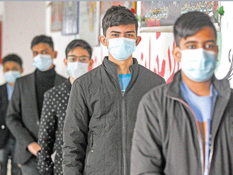 طلاب عراقيون بانتظار خضوعهم لفحص «كورونا» في مدرسة بمدينة الصدر في بغداد أمس                         (ا ف ب)