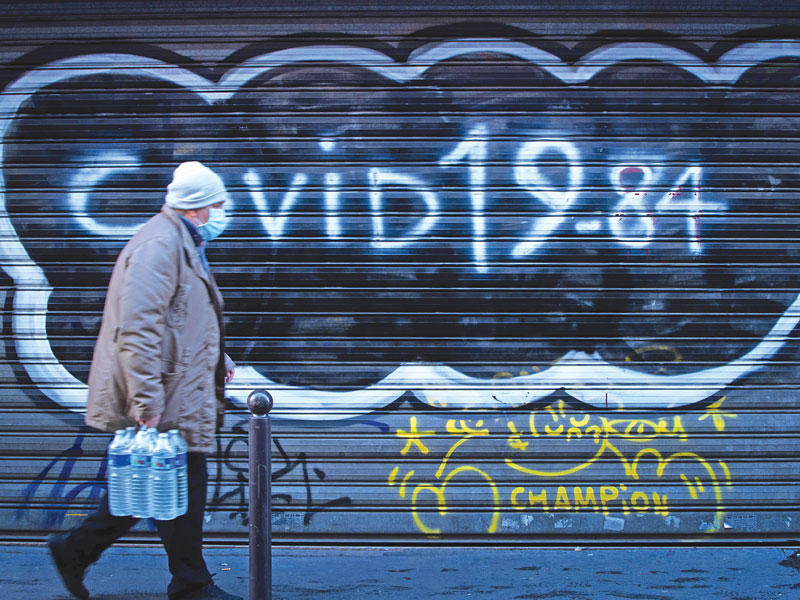 رجل يضع كمامة ويمرّ قرب رسمة على جدار كتب عليها «كوفيد 19 ـــ 84» في باريس أمس (أ ف ب)