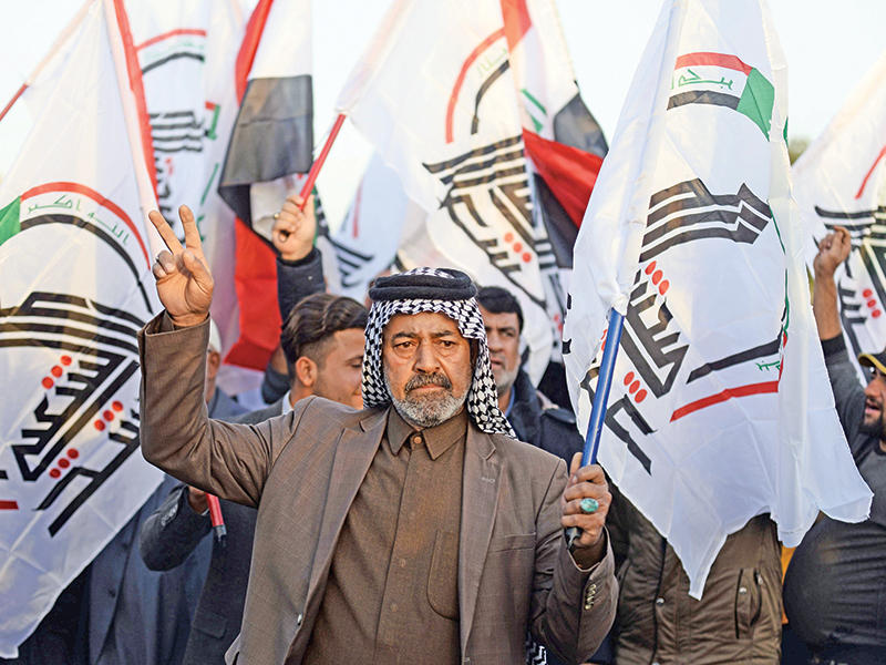 عراقيون يرفعون أعلام الحشد الشعبي (أ ف ب)