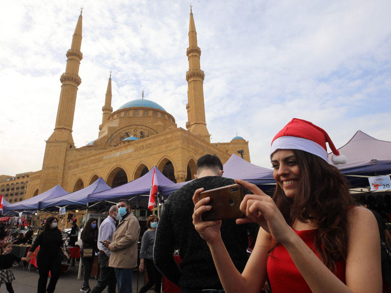 شابة لبنانية تلبس قبعة سانتا كلوز في «سوق الميلاد» قرب «مسجد الأمين» وسط بيروت أمس (ا ف ب)